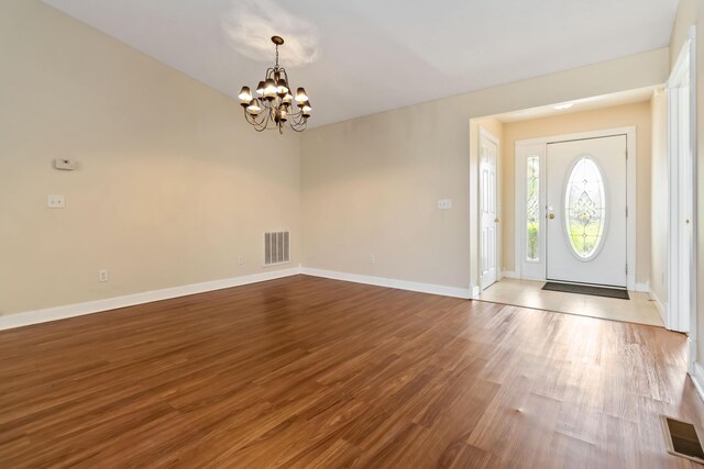 entrance foyer with visible vents, baseboards, wood finished floors, and an inviting chandelier