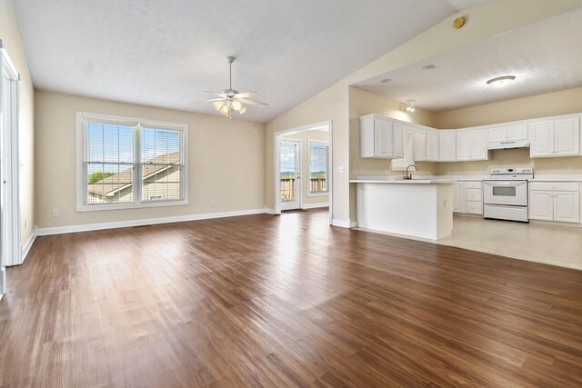 unfurnished living room with light wood-style floors, ceiling fan, vaulted ceiling, and plenty of natural light
