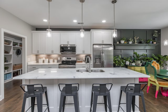 kitchen featuring appliances with stainless steel finishes, a sink, white cabinets, decorative backsplash, and recessed lighting