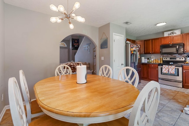 dining room with an inviting chandelier, arched walkways, a textured ceiling, and visible vents