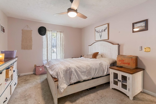bedroom featuring a textured ceiling, ceiling fan, light colored carpet, and baseboards