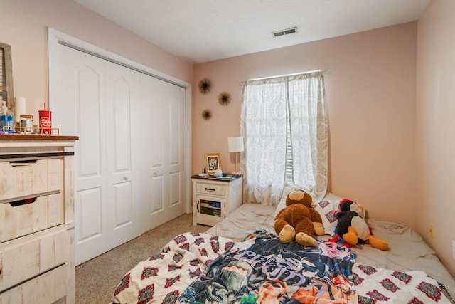 bedroom featuring carpet flooring, visible vents, and a closet