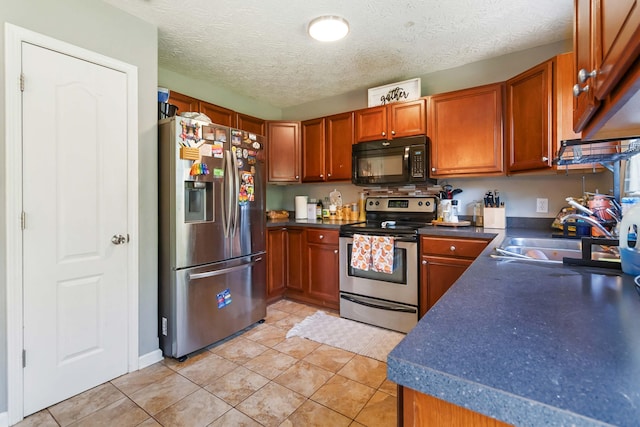 kitchen with a sink, light tile patterned floors, dark countertops, and stainless steel appliances