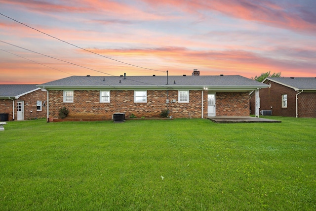 136 Pin Oak Dr, Lancaster, KY 40444 - back of house at dusk with a chimney, a lawn, brick siding, a patio, and central AC