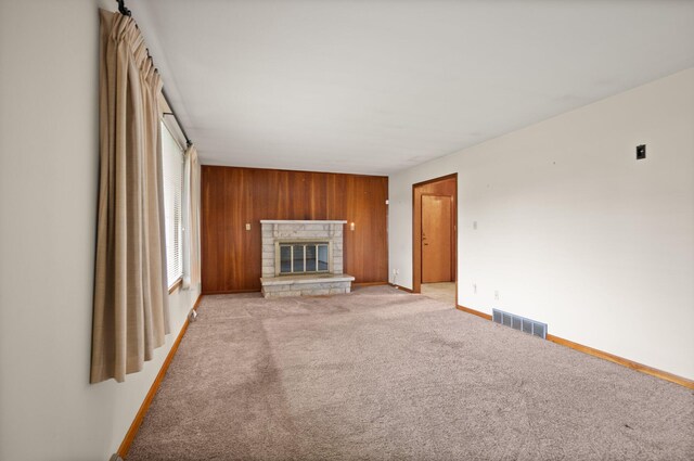 136 Pin Oak Dr, Lancaster, KY 40444 - unfurnished living room with wood walls, light colored carpet, visible vents, a fireplace, and baseboards