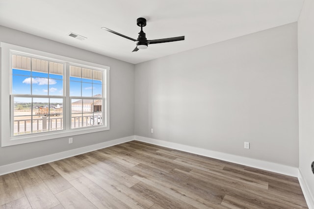 unfurnished room with a ceiling fan, baseboards, visible vents, and wood finished floors