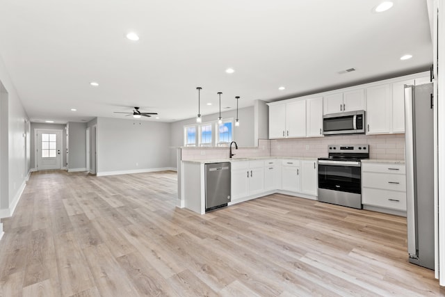 kitchen with open floor plan, ceiling fan, a sink, appliances with stainless steel finishes, and backsplash