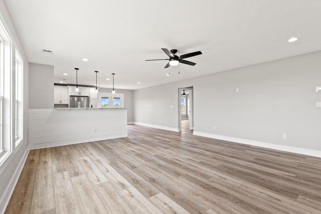 unfurnished living room featuring recessed lighting, ceiling fan, a wealth of natural light, and light wood-style floors