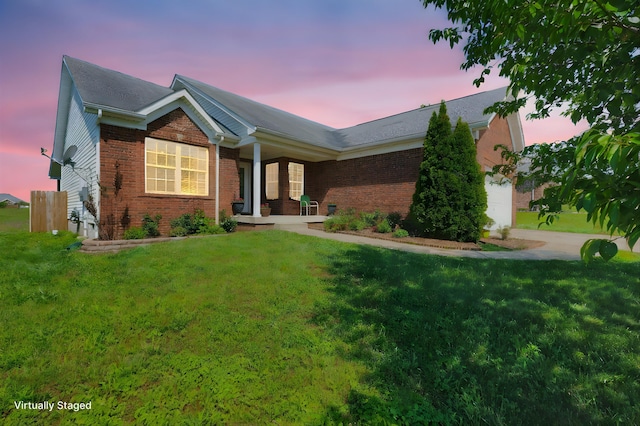ranch-style house with a lawn, brick siding, and a garage