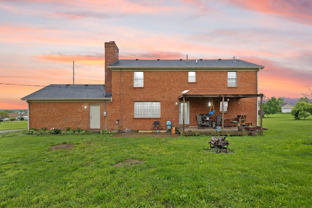 500 Curdsville Rd, Harrodsburg, KY 40330 - back of house at dusk with brick siding, a patio area, a chimney, and a lawn