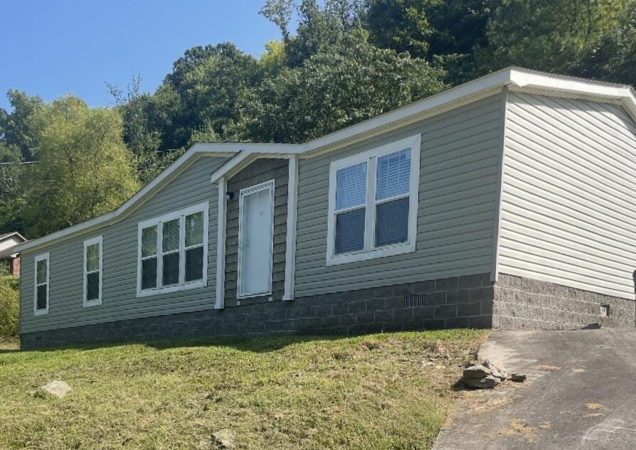view of side of property featuring a lawn and crawl space