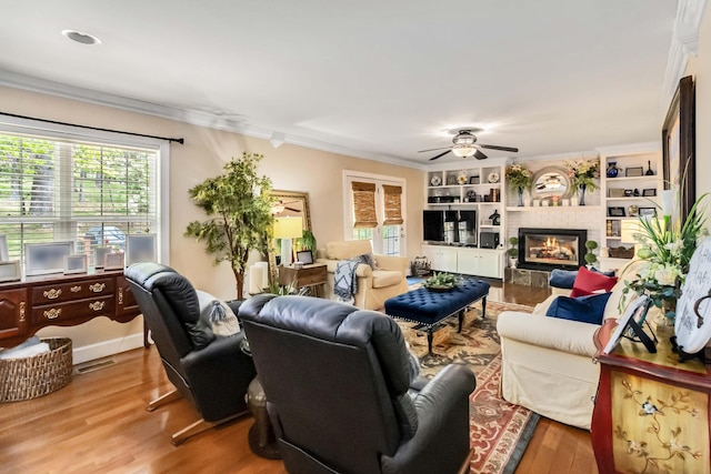 living area featuring crown molding, a wealth of natural light, and a ceiling fan