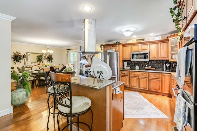 kitchen with brown cabinetry, a breakfast bar, stainless steel appliances, and island exhaust hood