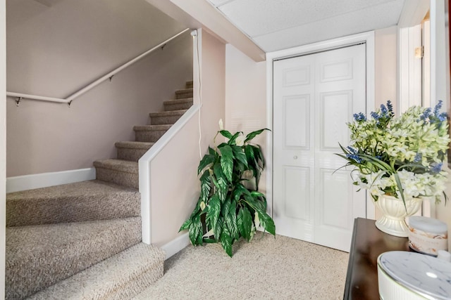 entrance foyer featuring stairs, carpet, and baseboards
