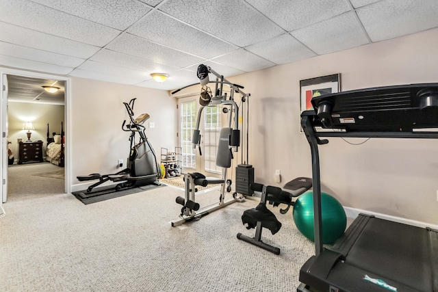 exercise area with a paneled ceiling, baseboards, and carpet floors