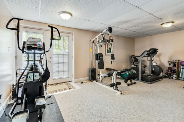 exercise room with a paneled ceiling, baseboards, and carpet floors