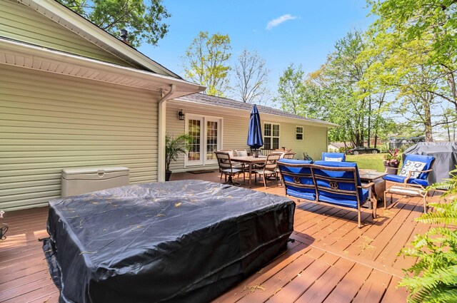 wooden terrace with a jacuzzi, outdoor dining space, and french doors