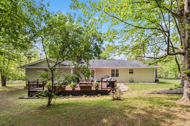 back of house featuring a chimney, a deck, and a lawn