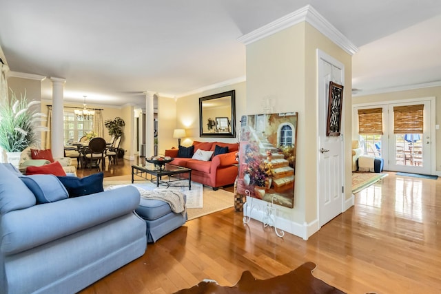 living room with ornamental molding, a healthy amount of sunlight, wood finished floors, and ornate columns