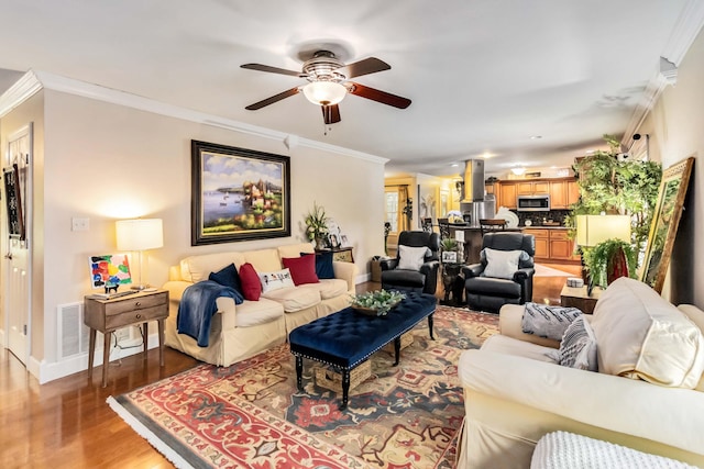 living room featuring baseboards, ceiling fan, light wood-style flooring, and crown molding