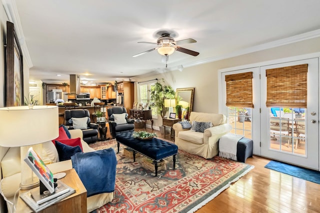 living area with crown molding, light wood-style flooring, and ceiling fan