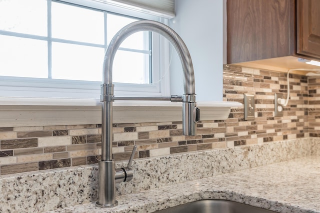 room details with a sink, light stone counters, and backsplash