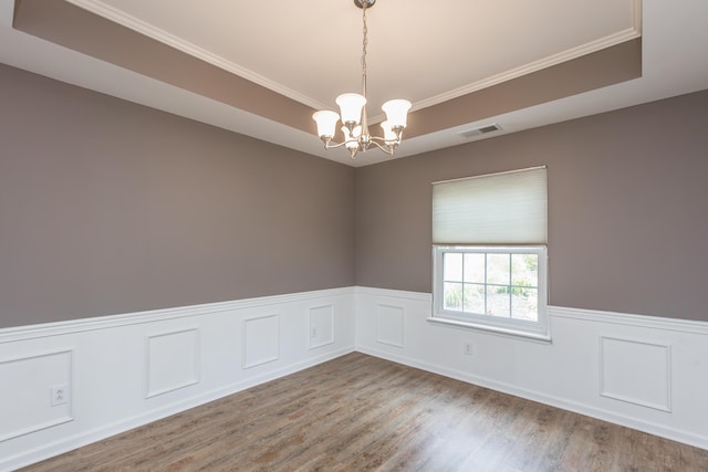spare room with an inviting chandelier, wainscoting, wood finished floors, and visible vents
