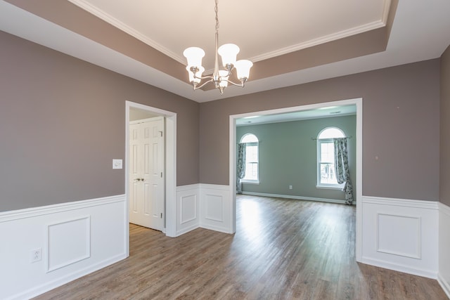 empty room with a wainscoted wall, wood finished floors, and a chandelier