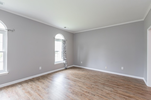 unfurnished room with crown molding, baseboards, wood finished floors, and visible vents