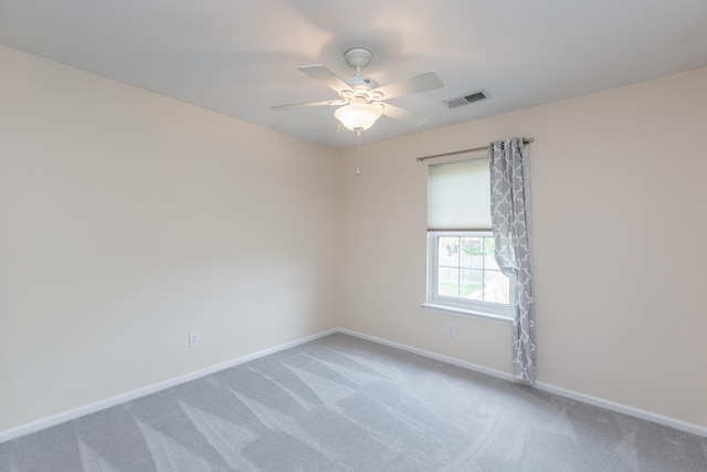 carpeted empty room with baseboards, a ceiling fan, and visible vents