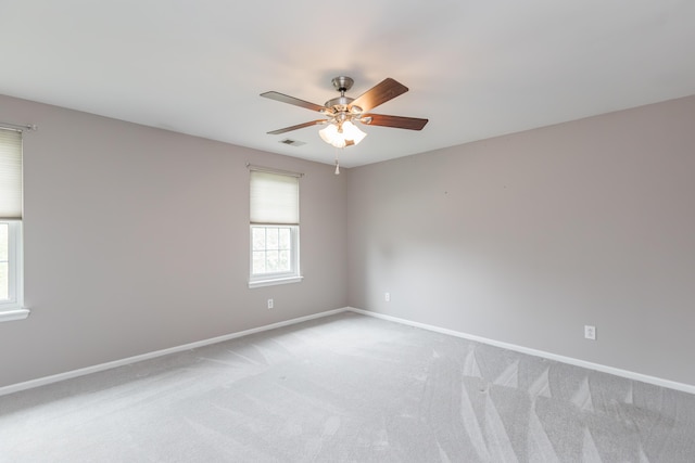 unfurnished room featuring a ceiling fan, baseboards, light colored carpet, and visible vents