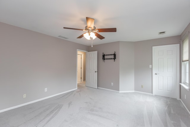 unfurnished room with a ceiling fan, light colored carpet, and visible vents