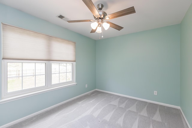 spare room featuring light colored carpet, ceiling fan, visible vents, and baseboards