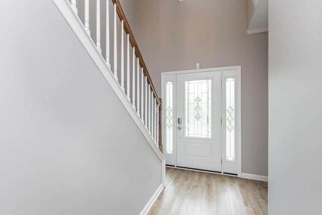 entryway with baseboards, stairs, wood finished floors, and a towering ceiling
