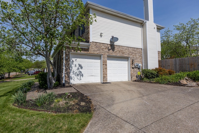garage featuring fence and concrete driveway