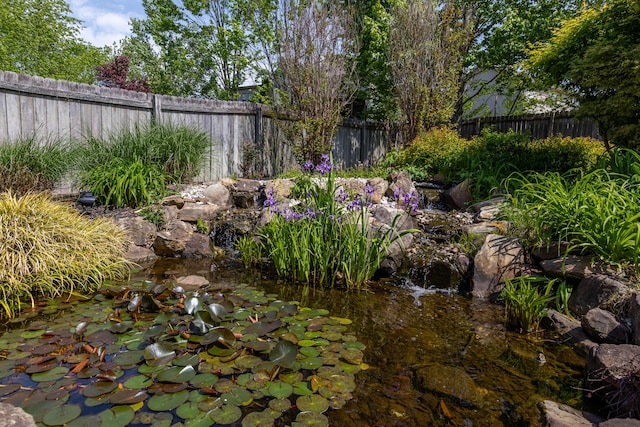 view of yard featuring a fenced backyard and a small pond