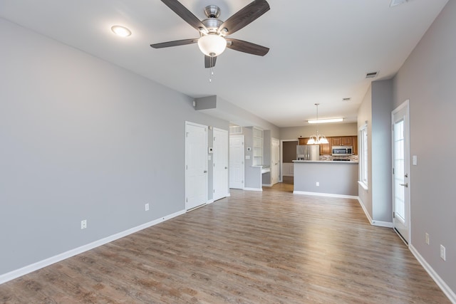 unfurnished living room featuring light wood-type flooring, a ceiling fan, baseboards, and visible vents