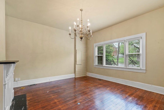 unfurnished dining area featuring baseboards, a chandelier, hardwood / wood-style flooring, and visible vents