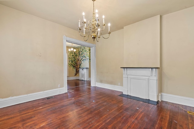 unfurnished dining area featuring an inviting chandelier, baseboards, hardwood / wood-style flooring, and visible vents