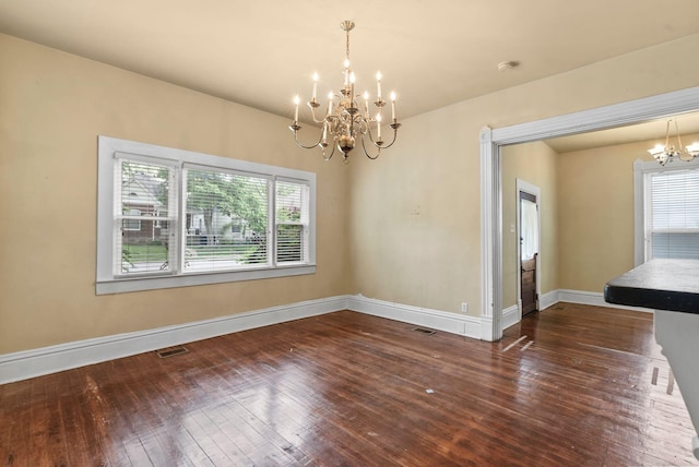 unfurnished dining area with an inviting chandelier, plenty of natural light, hardwood / wood-style flooring, and visible vents