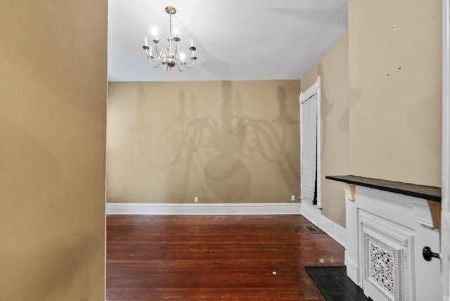unfurnished dining area with an inviting chandelier, baseboards, and hardwood / wood-style flooring