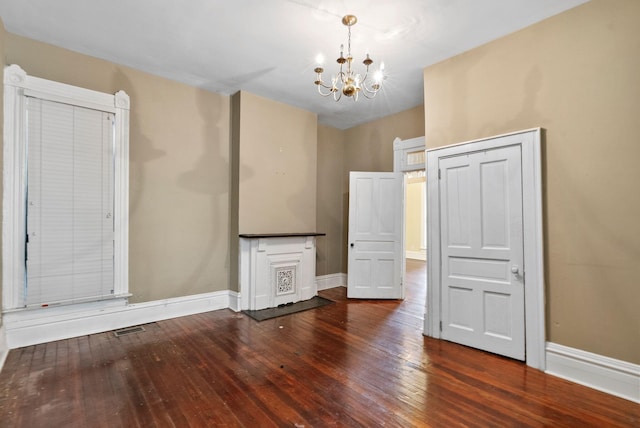 empty room with wood-type flooring, baseboards, a chandelier, and visible vents