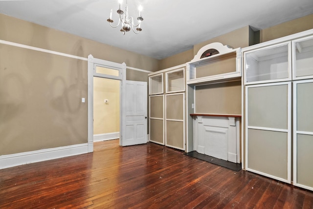 walk in closet with dark wood finished floors and a notable chandelier