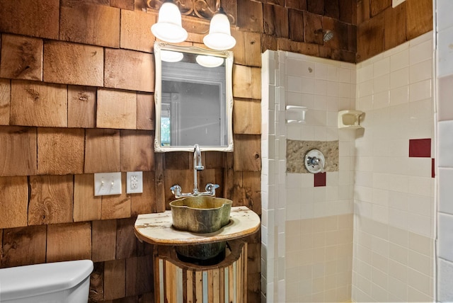 bathroom with a sink, a tile shower, and toilet