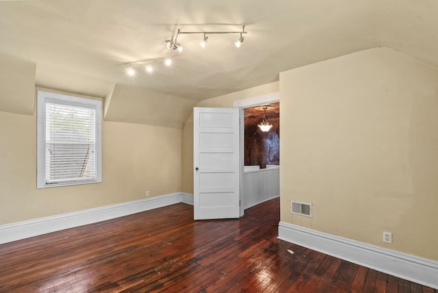 bonus room featuring dark wood-type flooring, baseboards, and vaulted ceiling