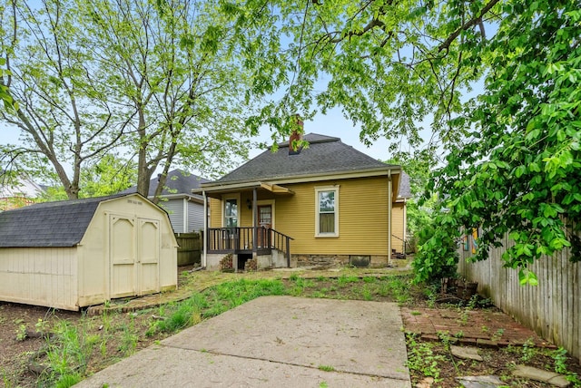 rear view of house with a fenced backyard, a shed, a chimney, a shingled roof, and an outbuilding