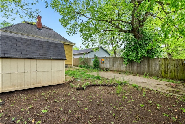 view of yard with a fenced backyard, an outbuilding, and a shed