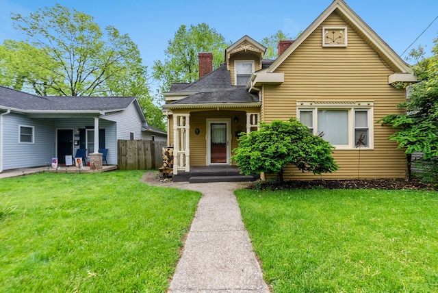 view of front facade featuring fence, a chimney, and a front yard