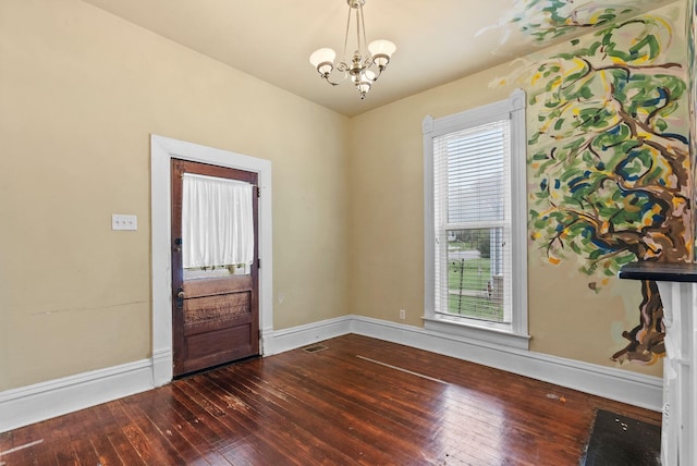 interior space featuring baseboards, a chandelier, a healthy amount of sunlight, and dark wood-type flooring