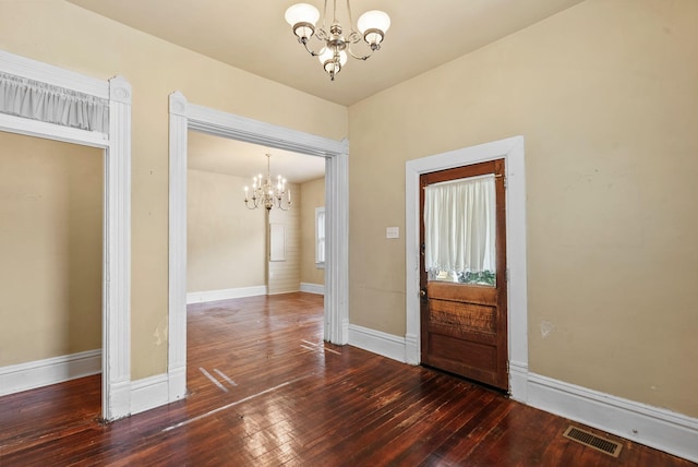 interior space with baseboards, visible vents, hardwood / wood-style floors, and a chandelier